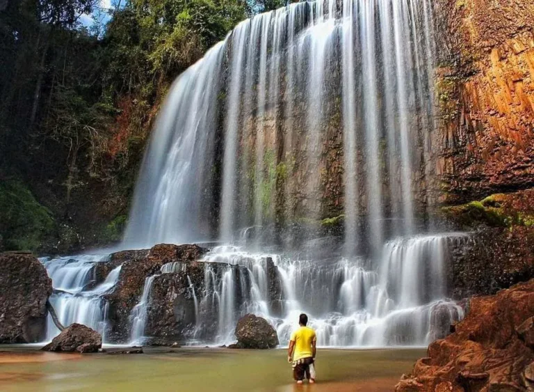 Cachoeira do Astor, com várias quedas de água sobre as pedras e uma pessoa no poço.