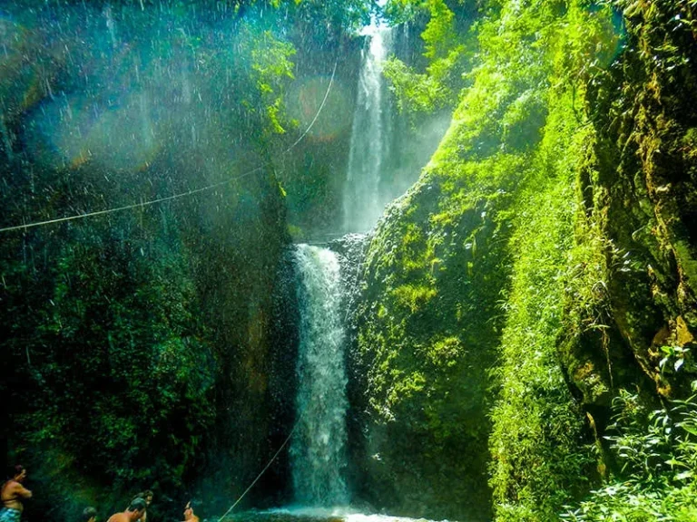 Cachoeira alta e fina no Ecoparque Cassorova, entre paredões cobertos de vegetação.