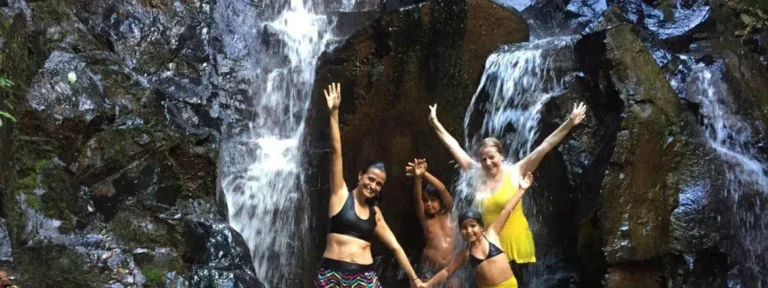 Grupo de amigos comemorando em frente a uma cachoeira no Viva Brotas Ecoparque.